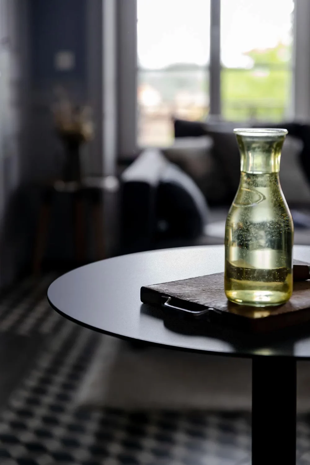 the round tray of the Donut table in close-up and on which rests a wooden cutting board and a bottle of water