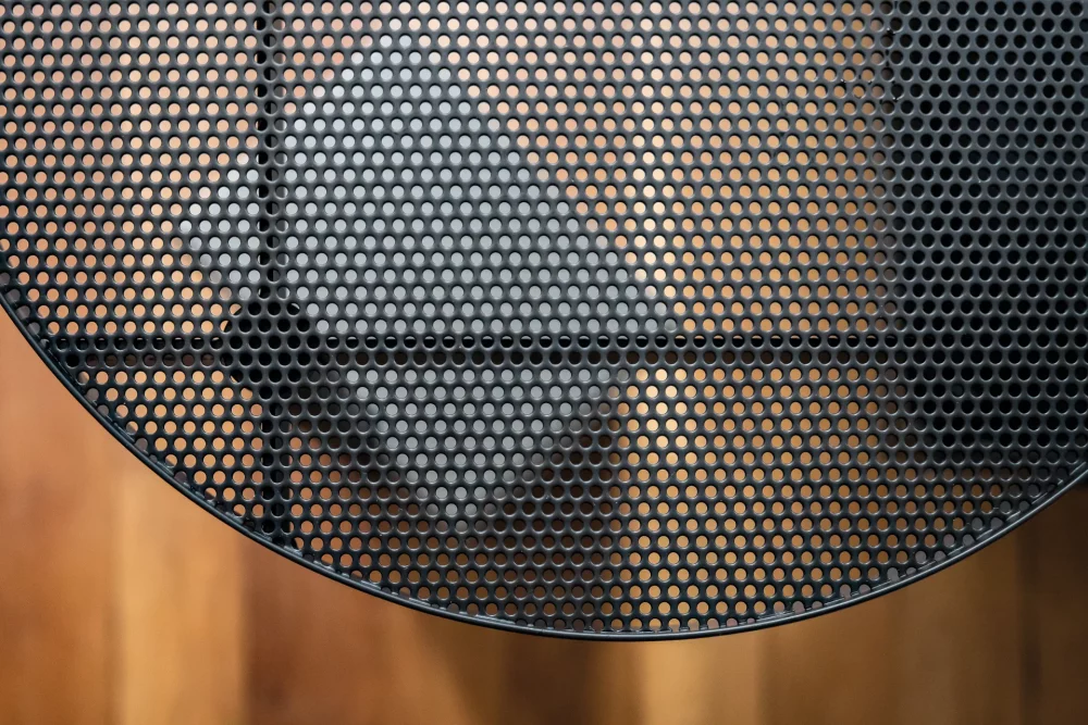 The perforated steel top of the Twist side table reveals the concrete structure and weight that make up its design