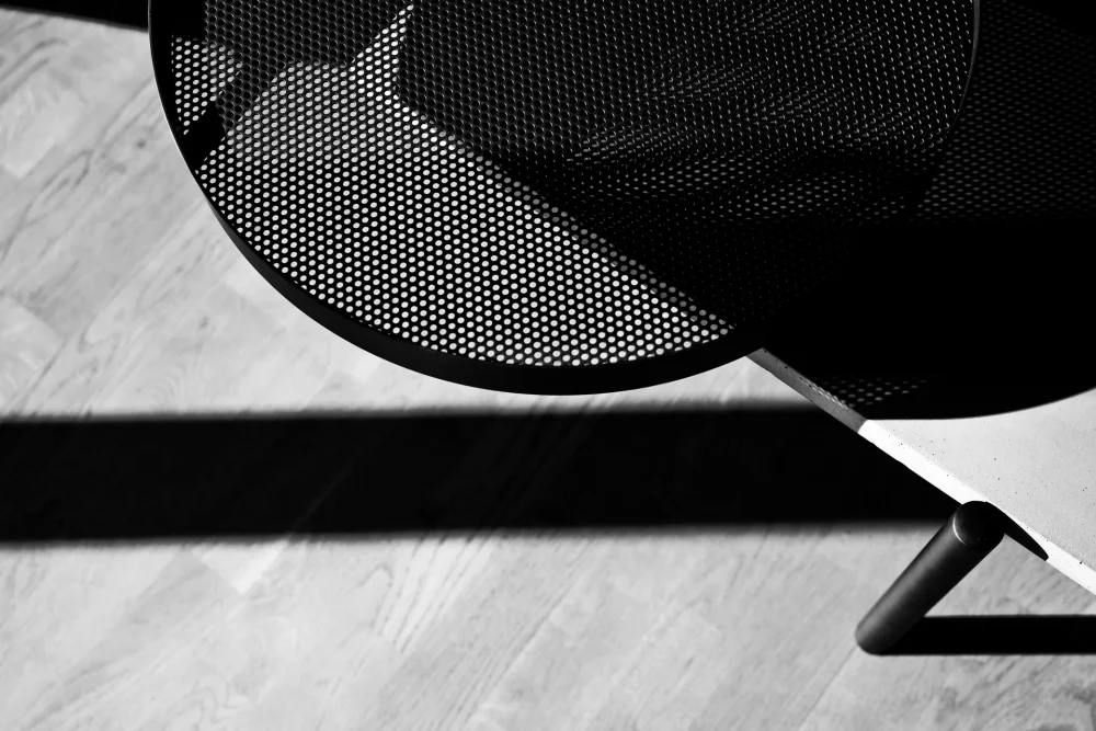 The perforated top of the removable tray of the Twist coffee table is perfectly highlighted in this black and white photo