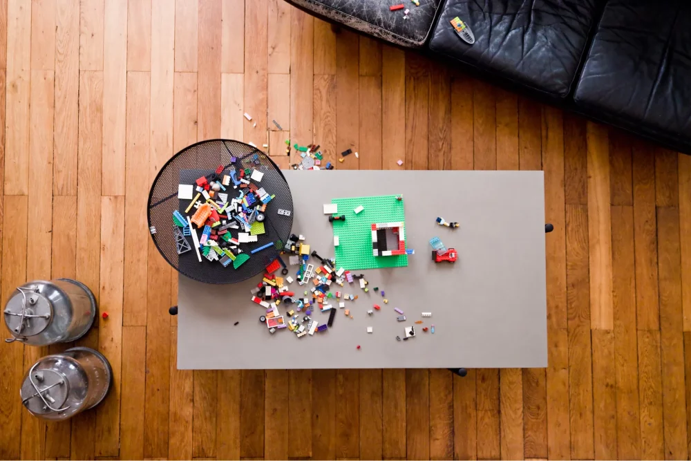 The concrete top of the Twist coffee table covered with Lego bricks next to a vintage leather sofa
