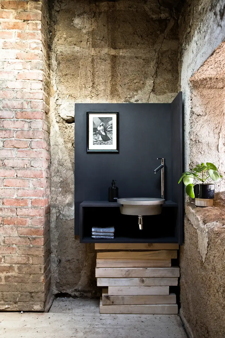 Industrial bathroom with exposed brick wall and concrete design accessories