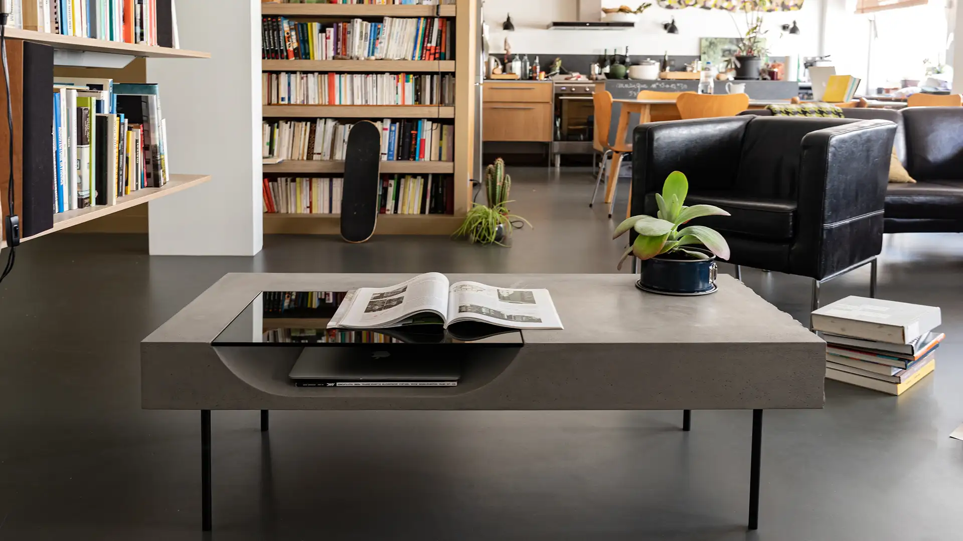 Concrete coffee table in a loft with bookshelf, black leather armchair and parquet — Lyon Béton