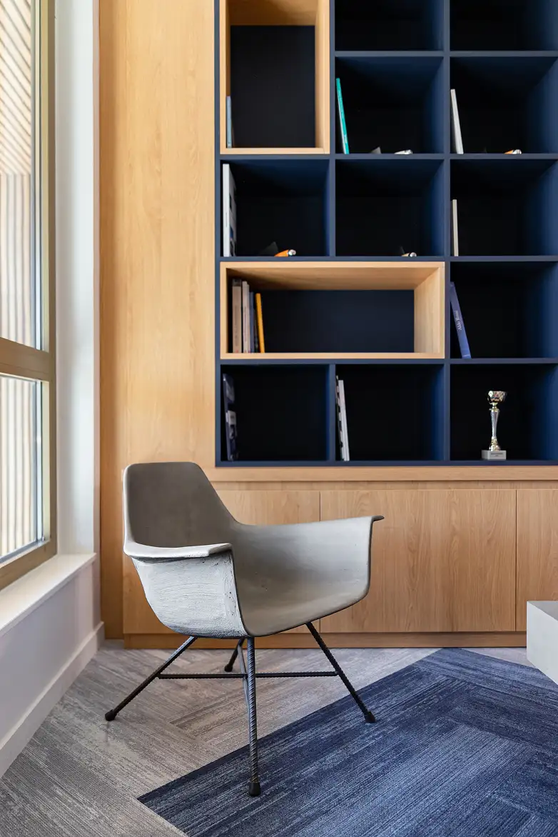 Hauteville concrete chair in front of a wood and navy blue bookcase — Lyon Béton concrete wood decoration