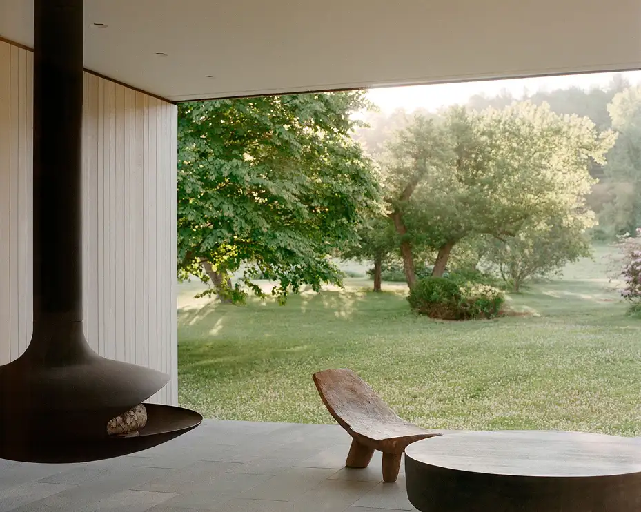 Minimalist interior combining concrete and wood with suspended fireplace and garden view