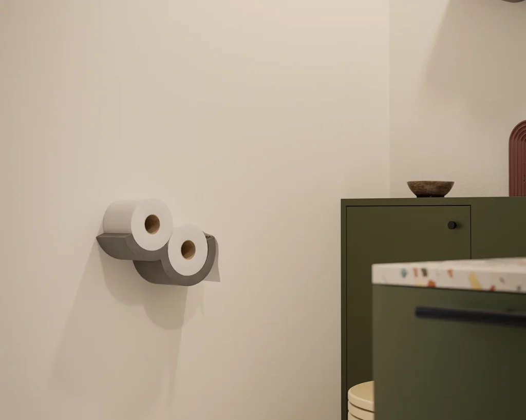 Grey concrete Cloud toilet paper dispenser on the wall, holding two rolls.