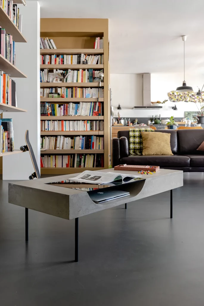 Concrete Curb coffee table with a glass-topped niche, in a living room with a bookcase.