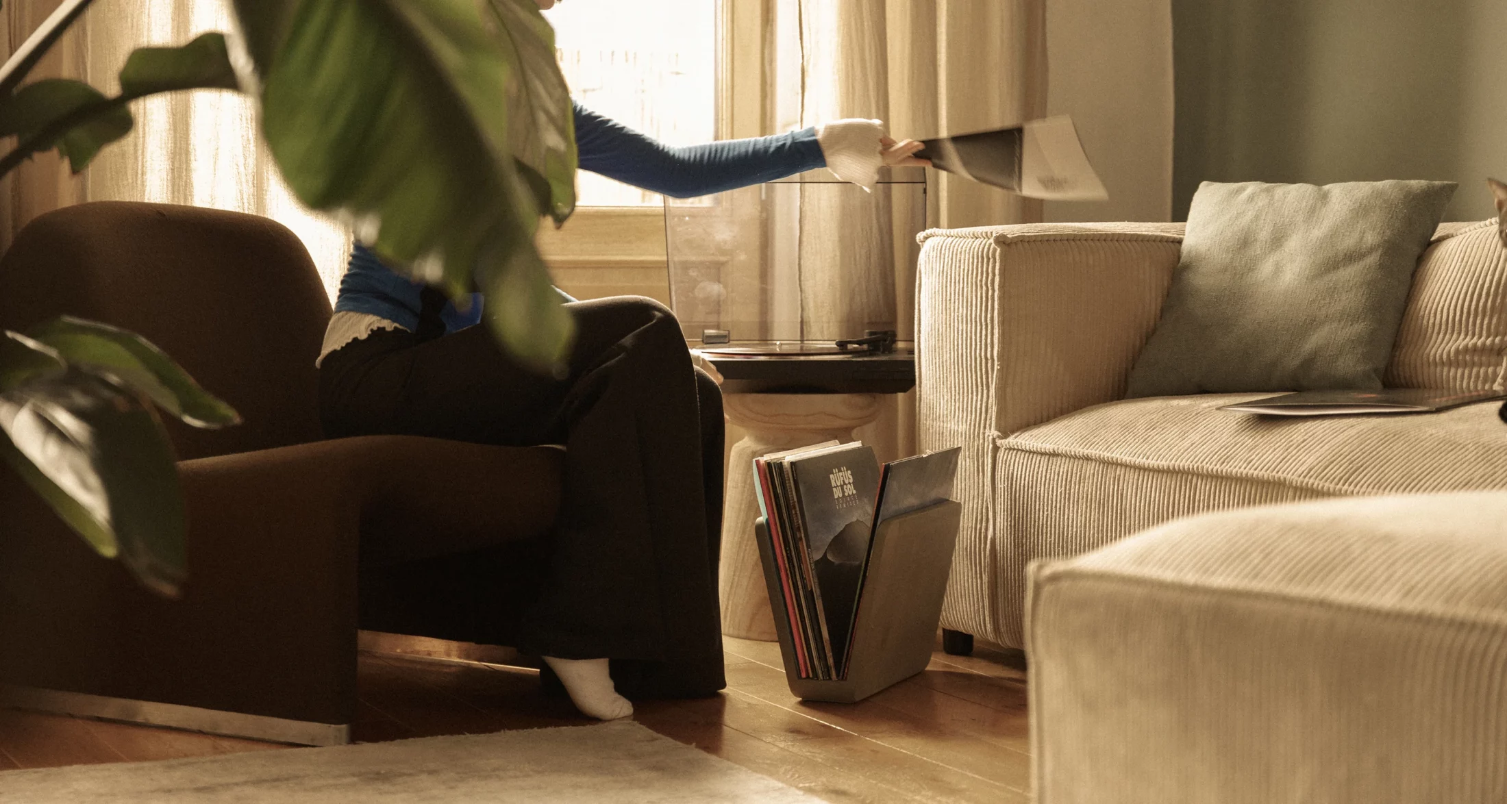 Concrete Doc magazine rack holding vinyl records on the floor next to a turntable.